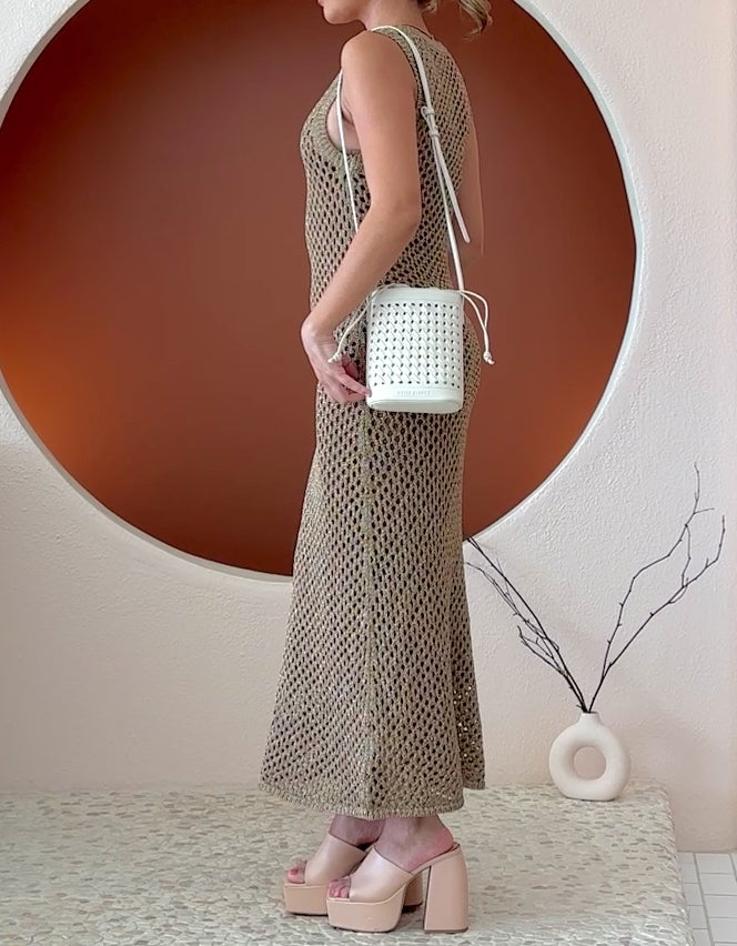 Video of a model wearing a small white woven vegan leather crossbody pouch with a drawstring closure.