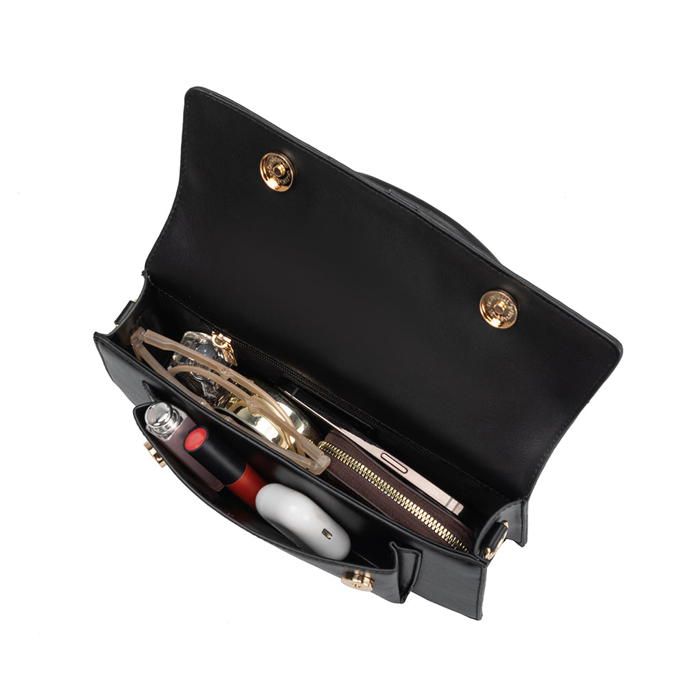 An inside view image of a small vegan leather rectangle shaped top handle bag with a wallet, phone, and makeup inside.